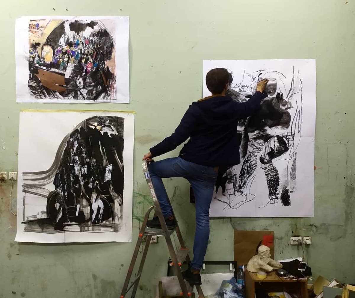 Artist on ladder before canvas