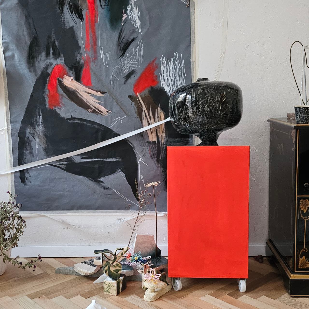Dark ceramic form on a red studio pedestal
