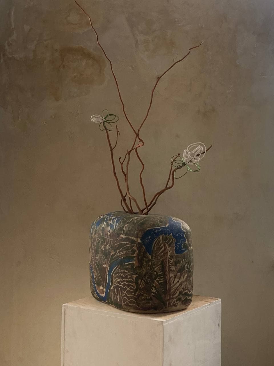 Sculptural ceramic vessel with branches on a pedestal
